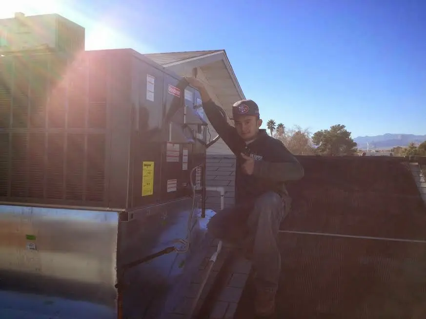 HVAC technician performing Boiler Repair on a rooftop unit in Alice